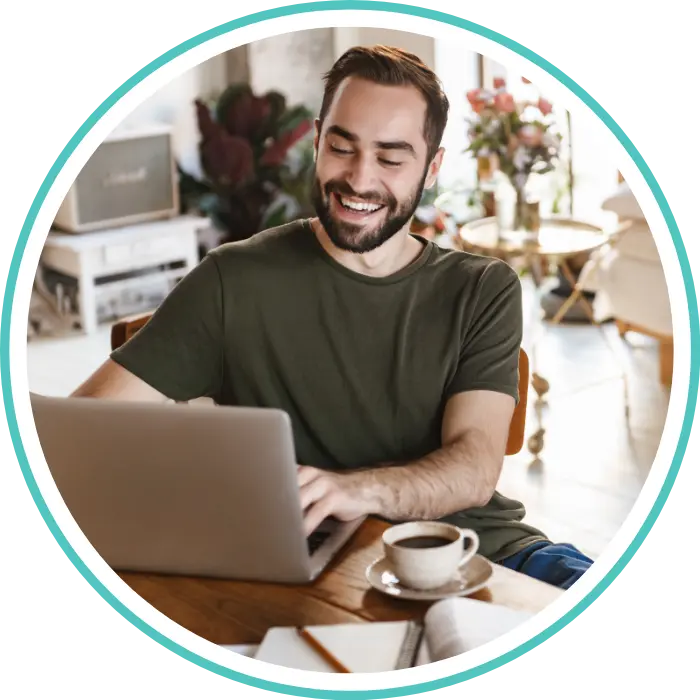 Happy man using laptop at home to make an NDIS referral