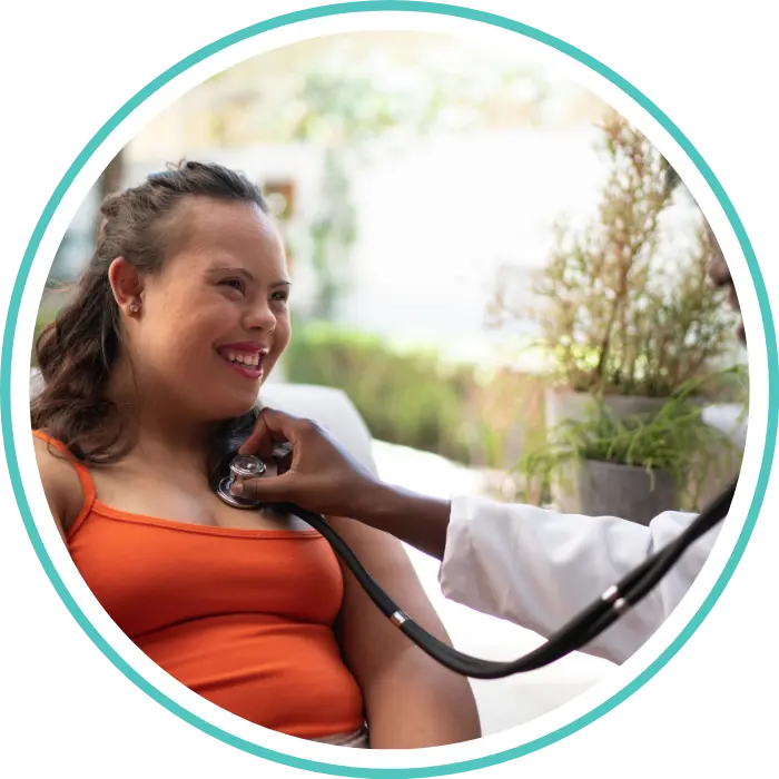 Happy disabled girl with down syndrome smiling while nurse listens to heartbeat